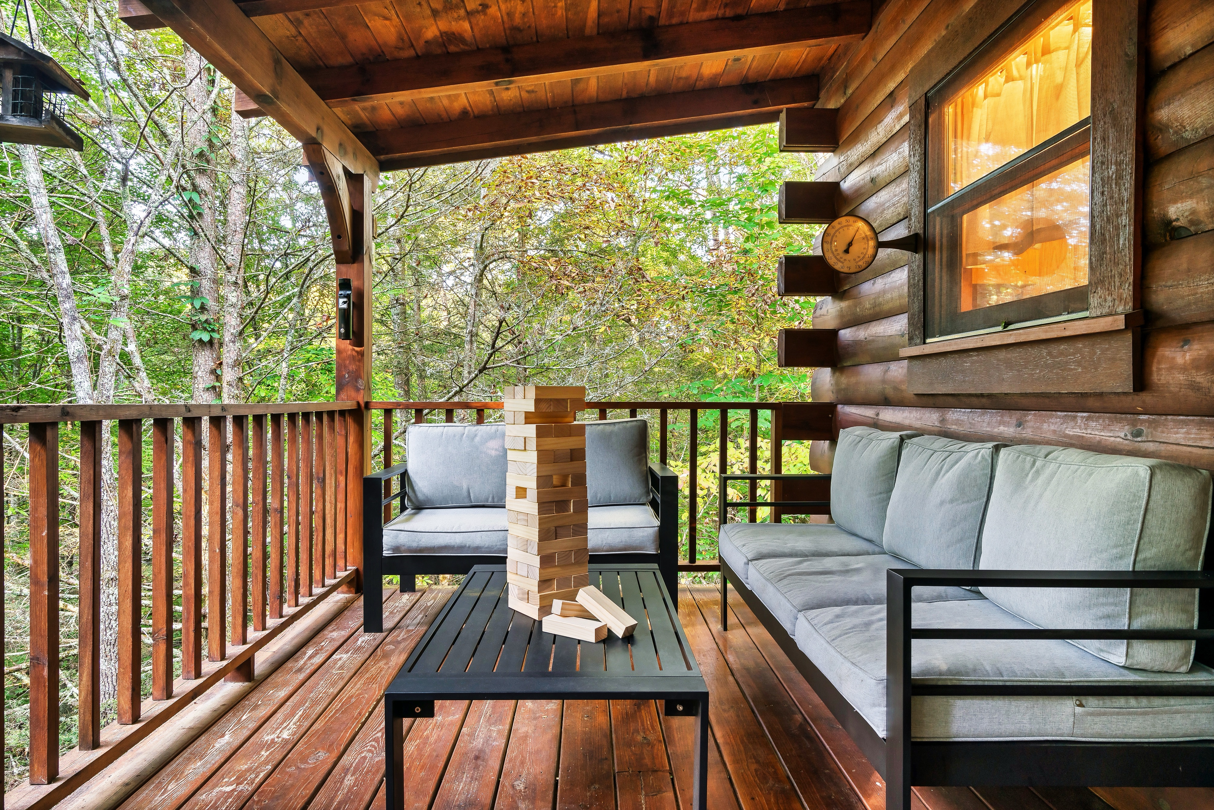 Covered deck lounge area with outdoor sofa and giant Jenga